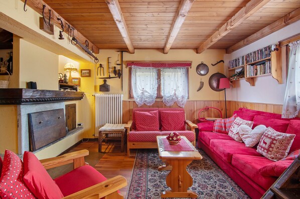 A cozy living room with a fireplace, a red sofa, a wooden bench, and a bookshelf.