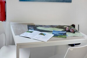 Un bureau blanc, avec des magazines ouverts et une paire de sandales.