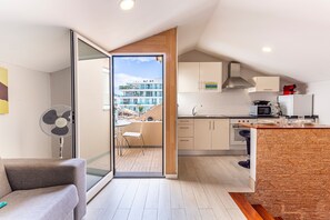 Cozinha moderna com área de jantar, um ventilador e vista para um edifício através de uma porta de vidro.