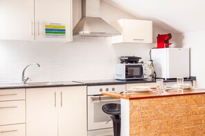 Cozinha moderna com micro-ondas, chaleira e um secador de cabelo vermelho em cima do balcão.