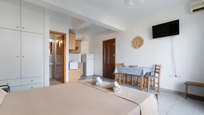 Une chambre à coucher avec un lit, une table à manger avec des chaises, un téléviseur et une armoire.