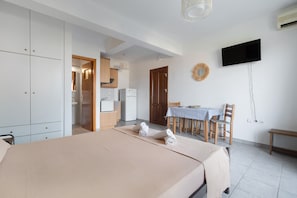 A bedroom with a bed, a dining table with chairs, a TV, and a wardrobe.