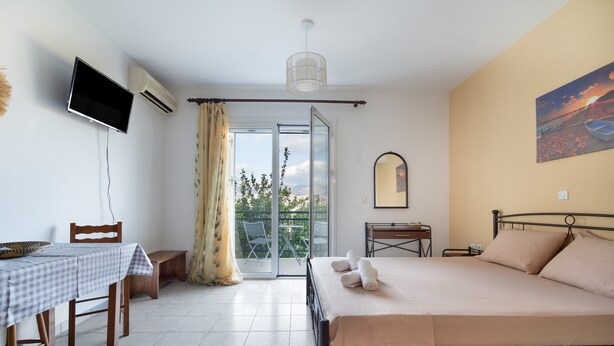 Une chambre à coucher avec un lit, une table et des chaises, une télévision et un tableau accroché au mur.