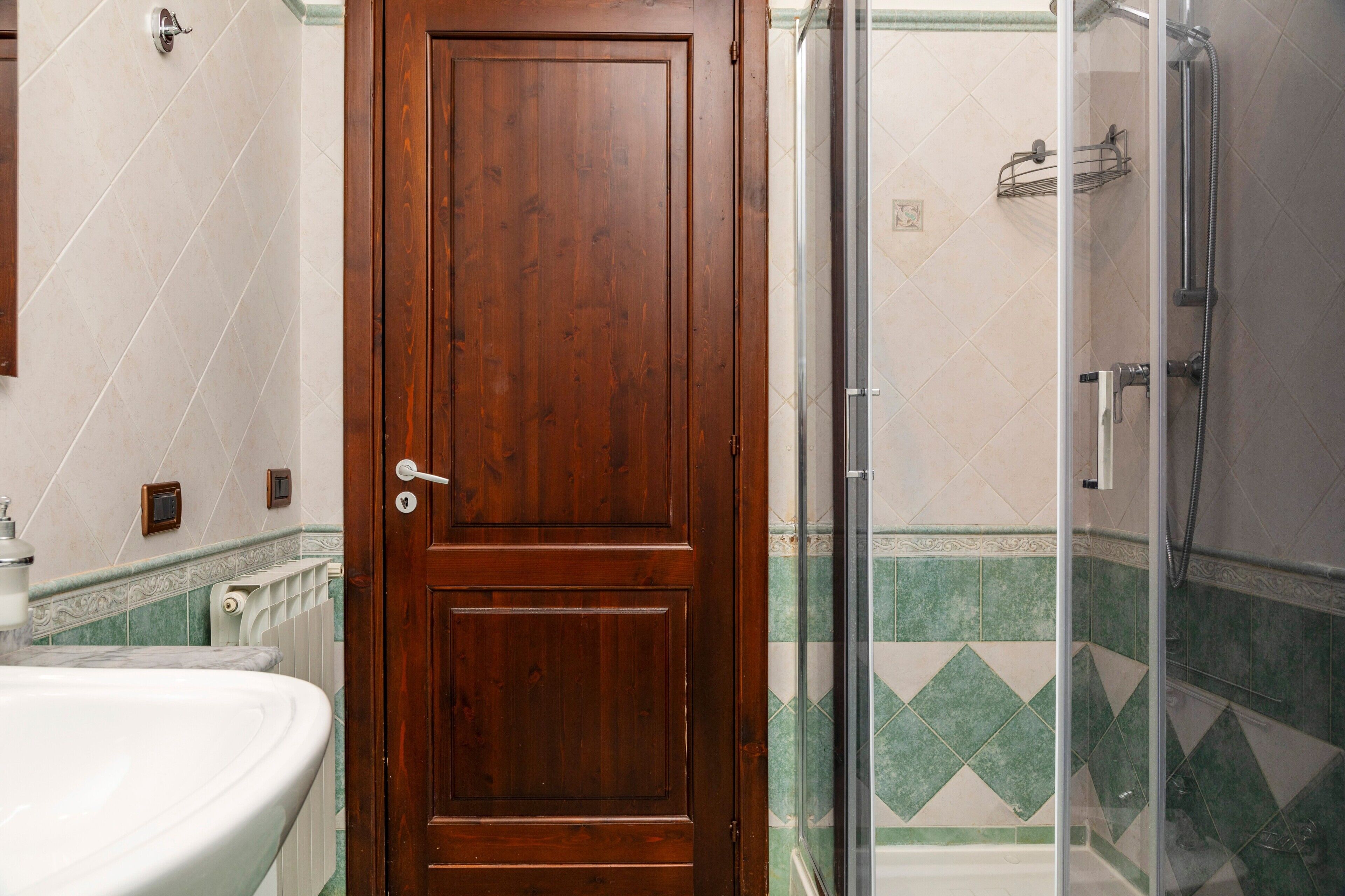 Un bagno con porta in legno, doccia e lavandino.