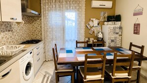 Une cuisine compacte comprenant un coin repas, un lave-linge et un réfrigérateur.
