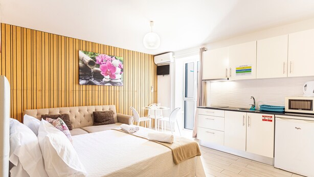 Une chambre d’hôtel comprenant un lit, un petit coin cuisine, une table à manger et un climatiseur fixé au mur.