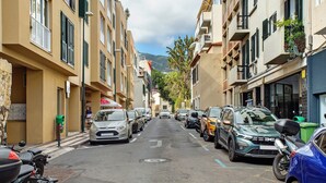 Une rue étroite bordée de voitures garées et d’immeubles dotés de balcons.