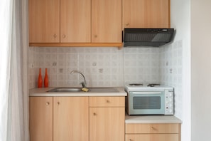 Une cuisine avec des meubles de rangement en bois, un évier, un four à micro-ondes et deux vases orange.