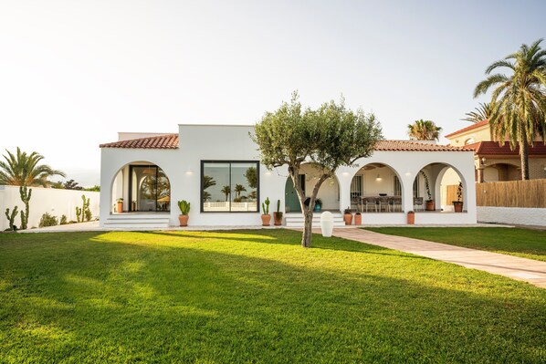 A modern house with a white exterior, large windows, and a well-maintained lawn.