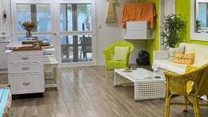 A room with a wooden floor, white furniture, a green wall, and a window with a cross decoration.