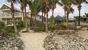 A resort with a sandy pathway, palm trees, and a building with a balcony.