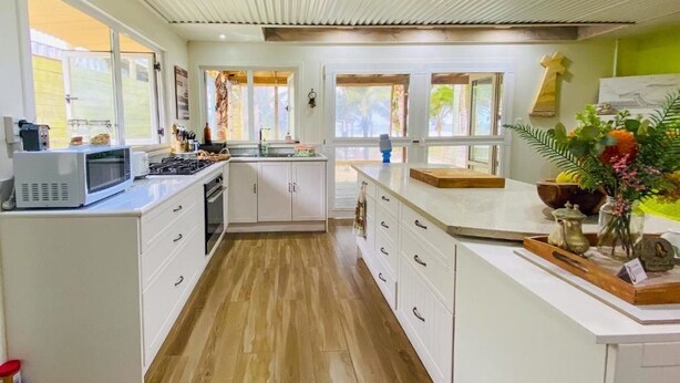 A modern kitchen with white cabinets, a central island, and a large window providing natural light.