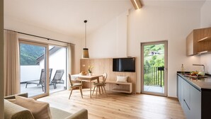 Una cocina moderna con televisor de pantalla plana, armarios de madera y un balcón con vistas panorámicas.