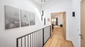 Een modern interieur met een houten trap, een eethoek en drie zwart-wit stadsgezicht schilderijen aan de muur.