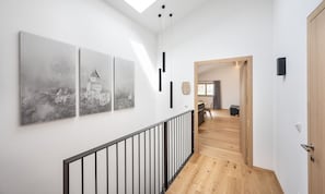 Ein modernes Interieur mit einer Holztreppe, einem Essbereich und drei schwarz-weißen Stadtbildern an der Wand.