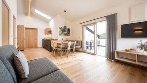 Een modern appartement met een eethoek, een bank, een televisie en een balkon met uitzicht.
