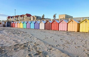 A row of colorful beach huts along a sandy beach, with buildings in the background. - Cozy apartment in Cucq with house a panoramic view (Cucq)