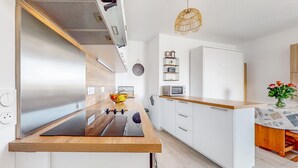Een moderne keuken met een houten aanrecht, witte kasten, een inbouwmagnetron en een hangende lamp.