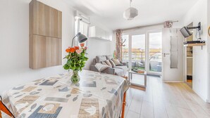 Een moderne woonkamer met een eettafel, bank en uitzicht op de stad door grote ramen.
