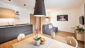 A modern kitchen with a dining table, chairs, and a pendant light.