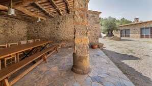 A stone building with a wooden table and benches, a stone pillar, and a clear view of the surrounding area.