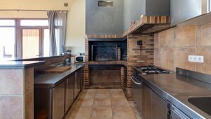 A modern kitchen with a brick fireplace, stainless steel appliances, and a large window.