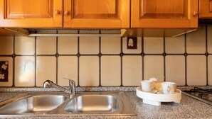 A kitchen with wooden cabinets, a stainless steel sink, and a granite countertop. - Apartment 'Chef House Sorso' with Shared Terrace and Private Garden (Sorso)