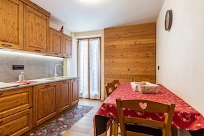 Una cocina con armarios de madera, un fregadero y una mesa con mantel rojo.