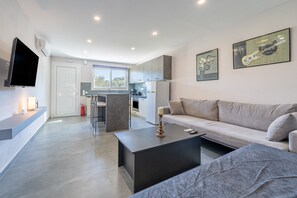 A modern living room with a sofa, coffee table, and a flat-screen TV mounted on the wall.
