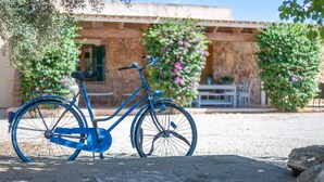 A blue bicycle parked in front of a building with a stone facade, a table, and chairs outside. - Country House 'Sa Vela' with Private Pool, Wi-Fi and Air Conditioning (Illes Balears)