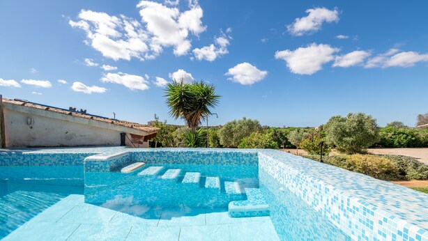 A swimming pool with blue mosaic tiles, a palm tree, and a clear sky. - Country House 'Sa Vela' with Private Pool, Wi-Fi and Air Conditioning (Illes Balears)