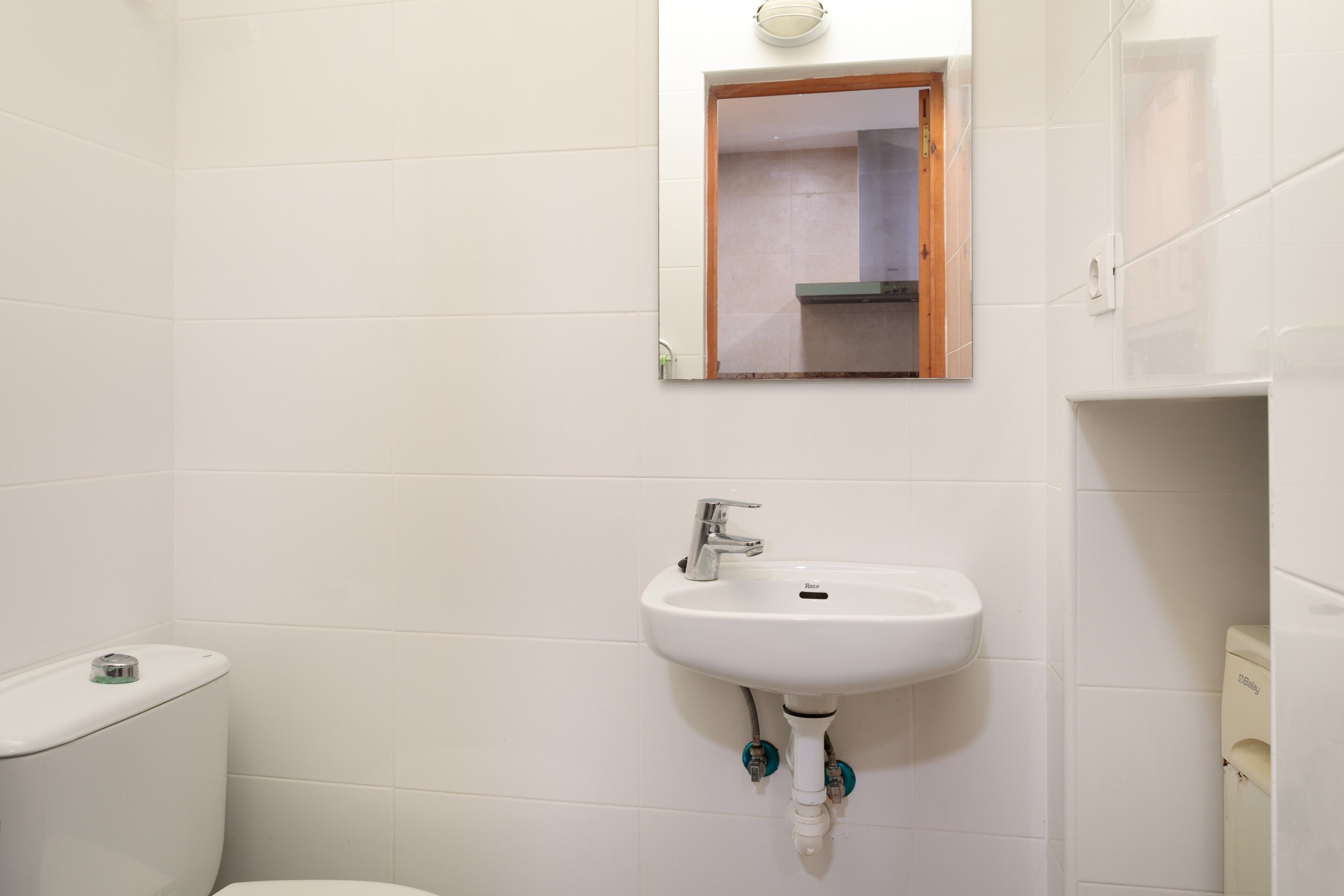 Een badkamer met een wit wastafel, een spiegel en een toilet.