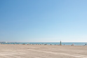 A beach with a volleyball net, a lifeguard tower, and a clear sky.