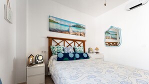Een slaapkamer met een bed, nachtkastjes, een schilderij, een spiegel en een klok.