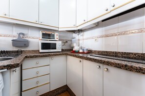 A kitchen with white cabinets, a granite countertop, a double microwave, and a coffee maker. - Apartment 'Benalmadenasol' with Shared Pool, Wi-Fi and Air Conditioning (Benalmádena)