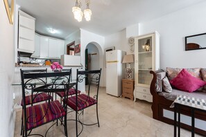 A compact living space with a dining area, kitchenette, and a sofa with cushions. - Apartment 'Benalmadenasol' with Shared Pool, Wi-Fi and Air Conditioning (Benalmádena)