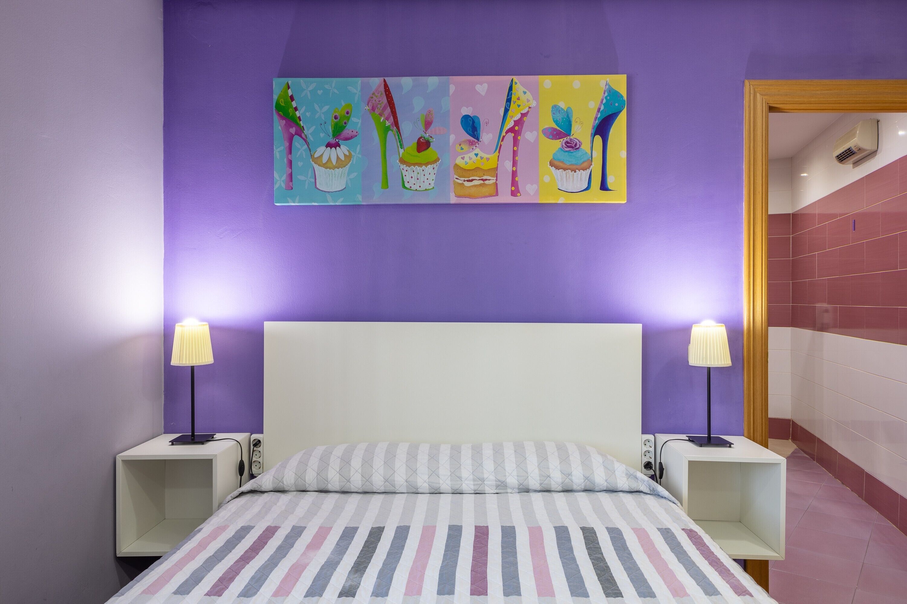 Ein Schlafzimmer mit einem Bett, zwei Nachttischen, einer Ablagefläche und einem Bettvorhang sowie einem an der Wand befestigten Kunstwerk.