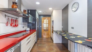A modern kitchen with a red countertop, stainless steel appliances, and a wooden door. - Casa Rural Kalfonso - 6-Bed Finca in Toledo Province, Private Garden & AC (Mascaraque)