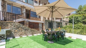 A patio with artificial grass, outdoor furniture, and a large umbrella. - Apartment 'Cal Confianza' with Mountain View, Private Garden and Wi-Fi (Borredà)