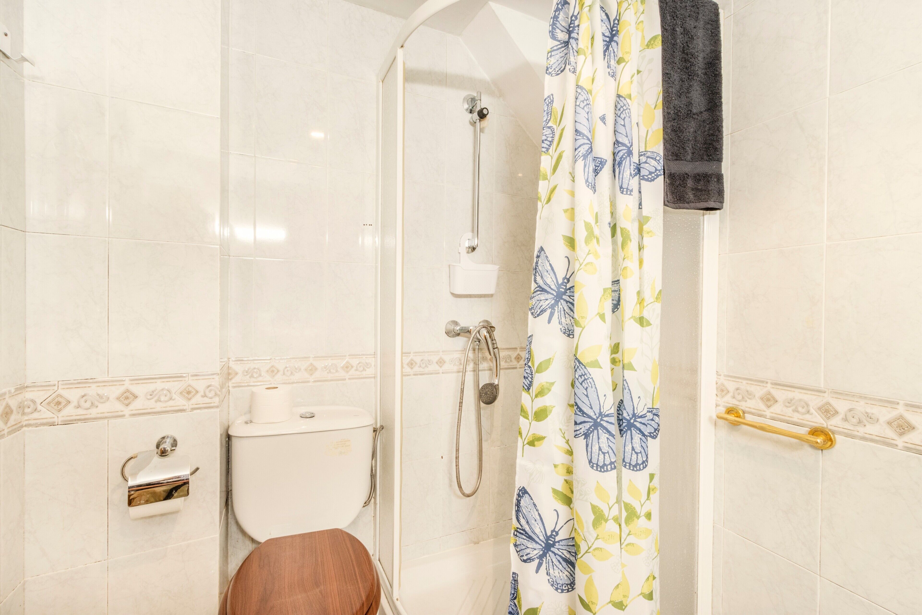 Un bagno con il water, doccia e porta asciugamani.