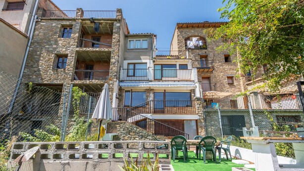 A courtyard with a green lawn, outdoor seating, and a stone wall. - Apartment 'Cal Confianza' with Mountain View, Private Garden and Wi-Fi (Borredà)