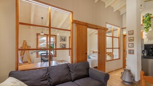 Ein Wohnzimmer mit einer Couch, Holzrahmen-Schiebetüren, einer Küchenzeile und einem Esstisch.