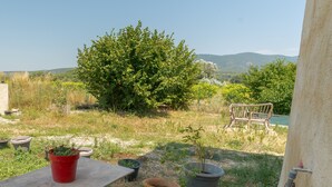 A garden with potted plants, a bench, and a view of distant hills. - Studio Apartment 'L'Amaryflor' with Private Garden (Vaugines)