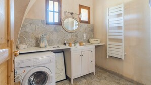 A compact bathroom with a washing machine, a sink with a mirror, and a towel rack. - Studio Apartment 'L'Amaryflor' with Private Garden (Vaugines)