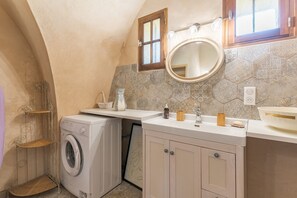 Uma casa de banho compacta com máquina de lavar, pia com espelho e janela.