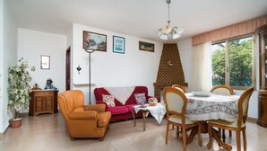 Een woonkamer met een bank, fauteuil, eettafel en een open haard.