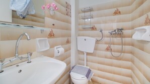 Et badeværelse med vask, toilet, bruser og et spejl.
