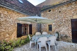 Un bâtiment en pierre avec une table et des chaises placées sous un auvent.