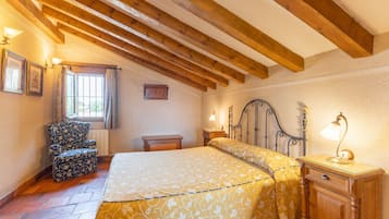 Une chambre à coucher avec un lit, une chaise, une table de chevet et une fenêtre avec des rideaux.