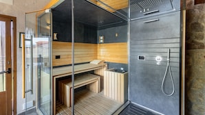 En sauna med glasvægge, træbænke og et bruseområde.
